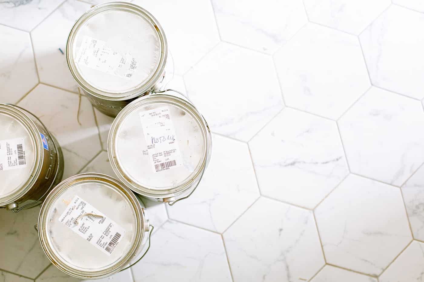 Seaux de peinture blanche posés sur un carrelage hexagonal