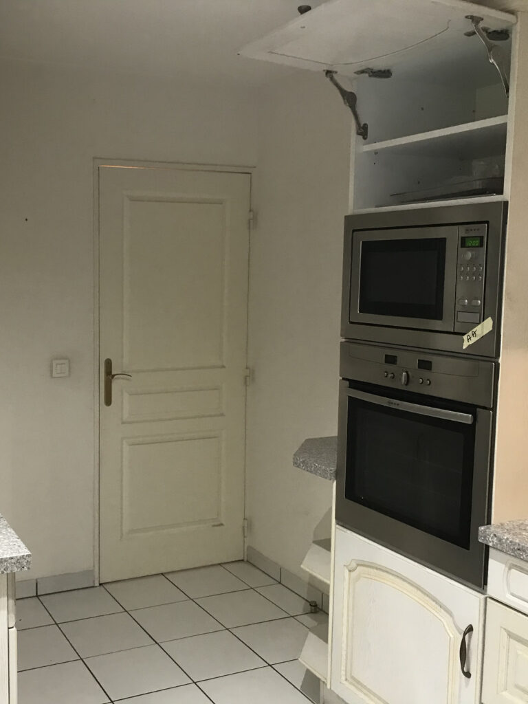 Vue de la cuisine avec porte et rangements anciens