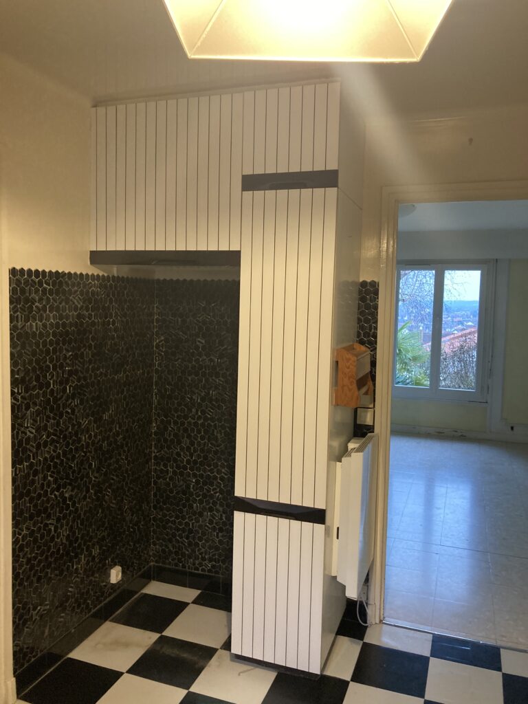 Vue d’une cuisine avant rénovation avec carrelage noir et blanc et crédence sombre