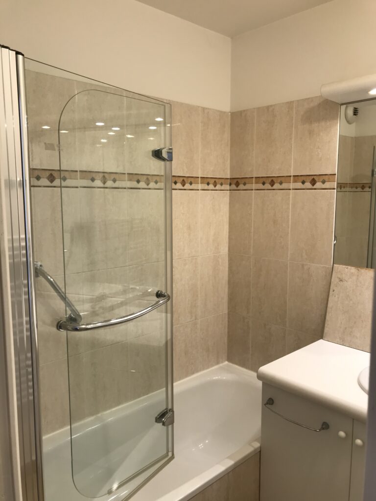 Ancienne baignoire avec carrelage mural beige à moderniser