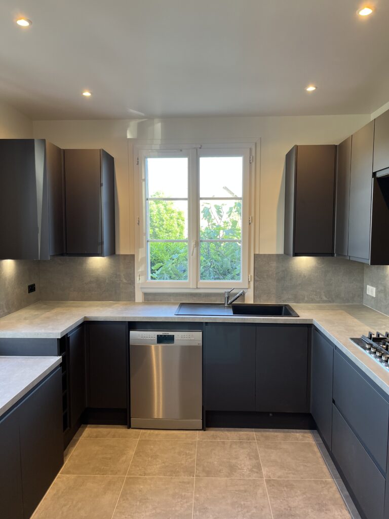 Cuisine rénovée avec meubles noirs mats et sol beige