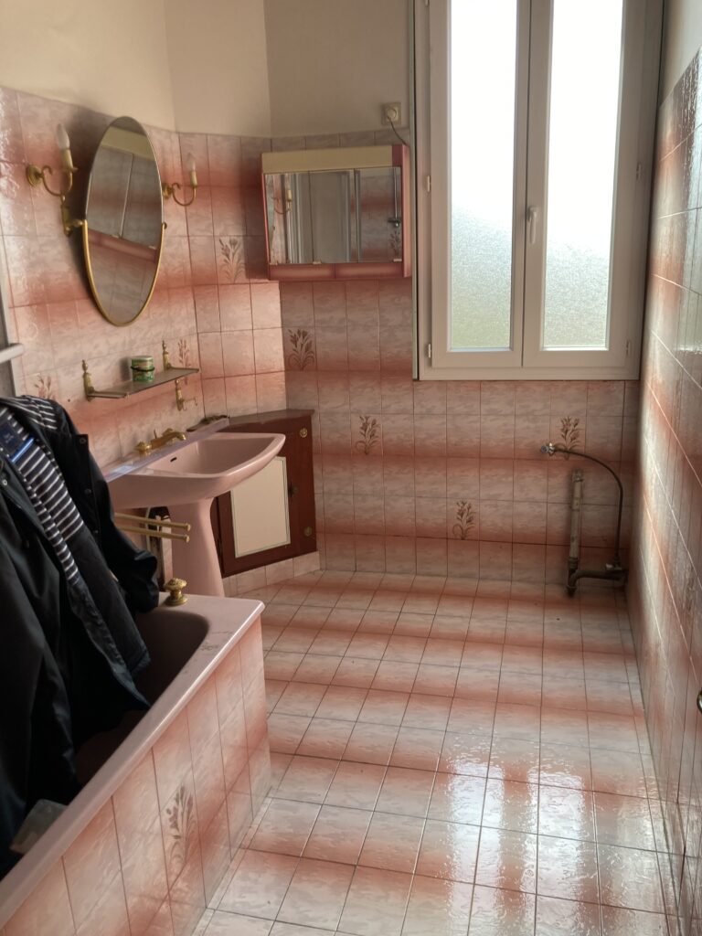Salle de bain ancienne avec carrelage rose et baignoire encastrée