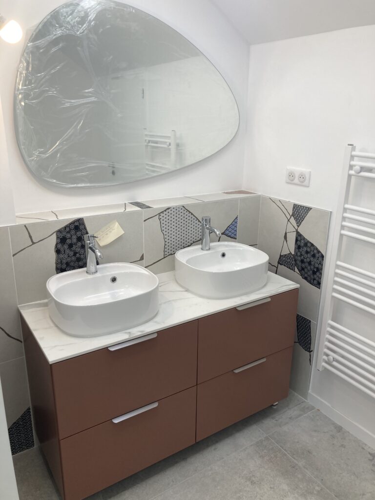Salle de bain rénovée avec meuble double vasque et miroir arrondi