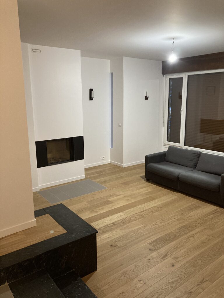 Salon rénové avec parquet bois et murs blancs