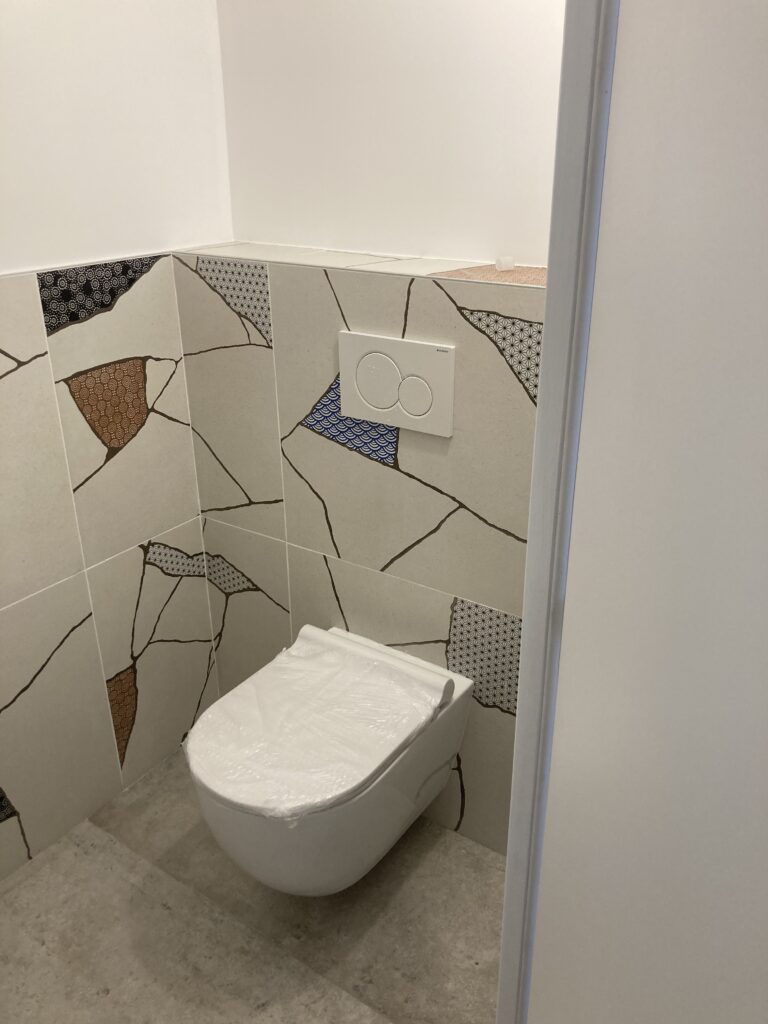 WC rénové avec carrelage mosaïque mural et cuvette suspendue